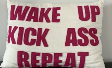 Pillow with writing on it: Wake up, Kick ass, Repeat