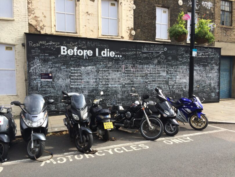 A chalkboard on a sidewalk in London with the prompt, "Before I die"