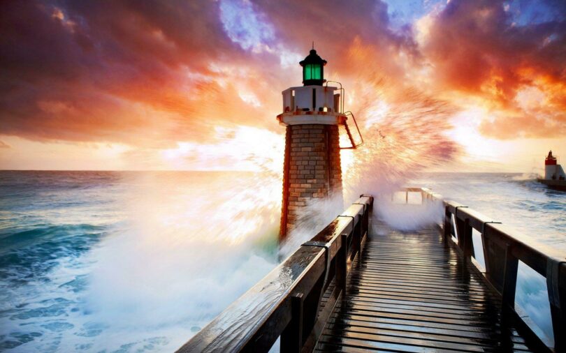 Photo of a light house, stormy sea, and sunrise