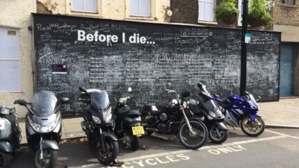 A chalkboard on a sidewalk in London with the prompt, "Before I die"